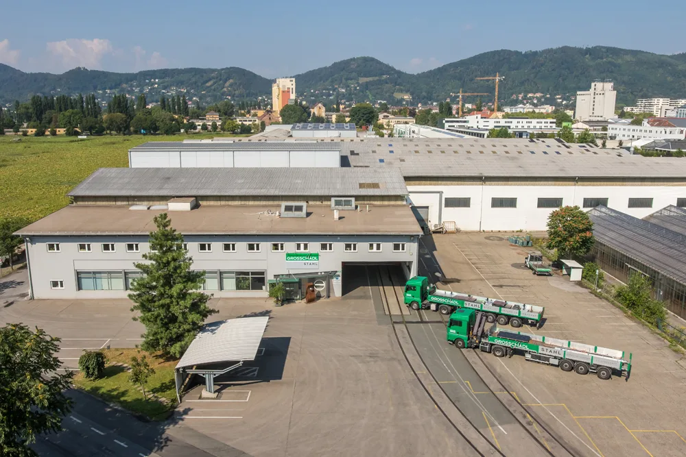 Luftaufnahme des Grazer Betriebs mit Hallen und grünen Lastwagen